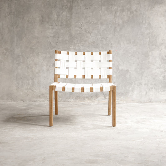 Chair with woven seat and backrest against a gray concrete wall.