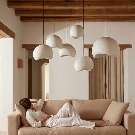 Woman lying on a beige sofa in a modern living room with pendant lights and decorative vases.