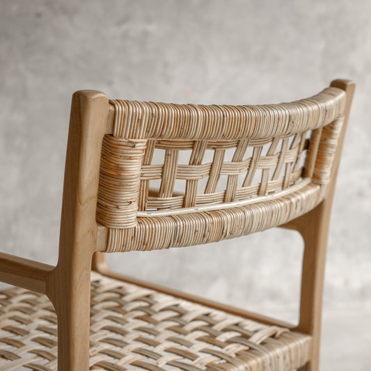 Wooden chair with wicker backrest against a neutral background