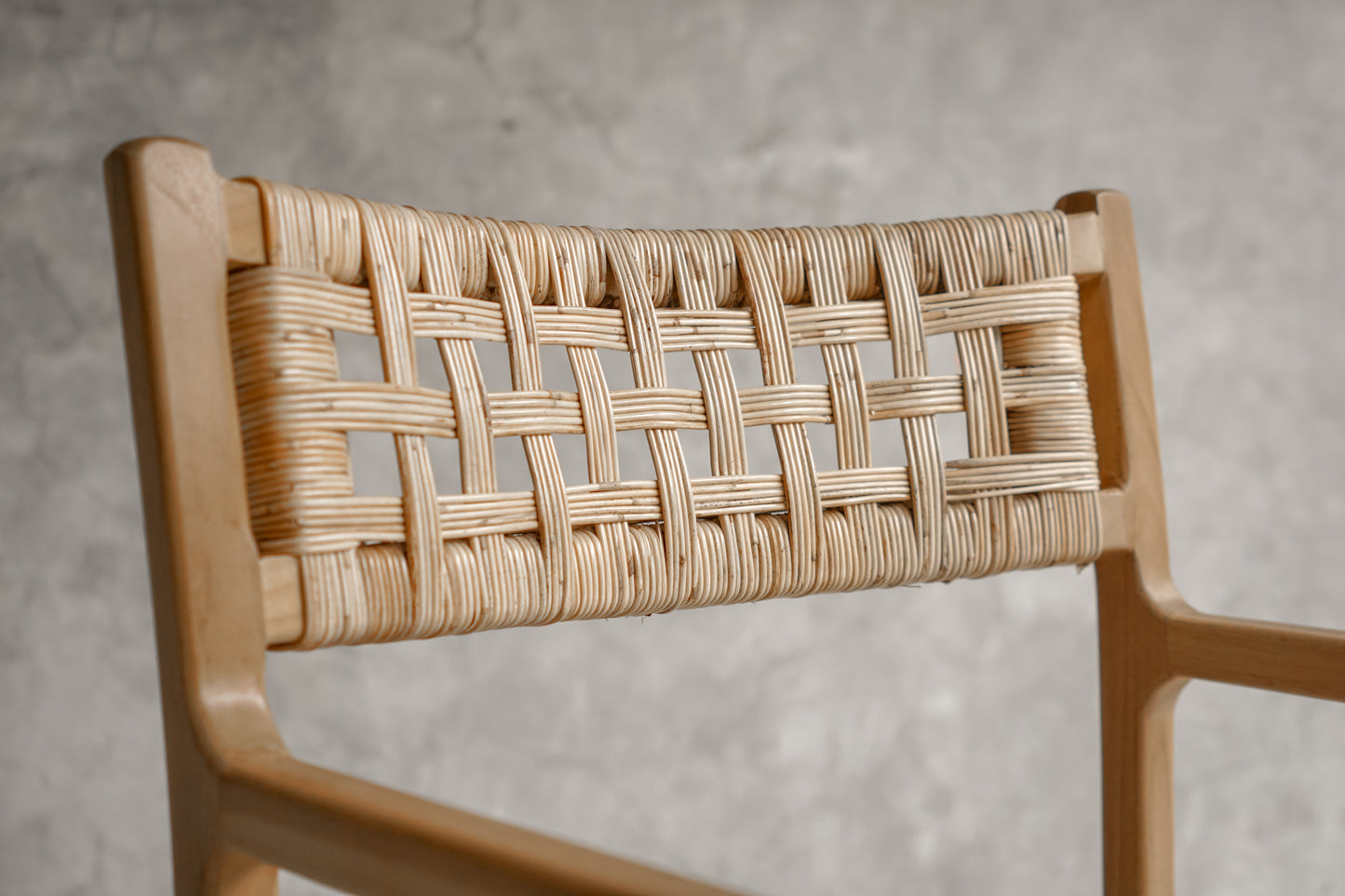 Wooden chair with woven backrest against a gray background