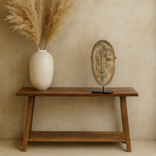 Wooden console table with a vase of pampas grass and a decorative mirror against a beige wall.