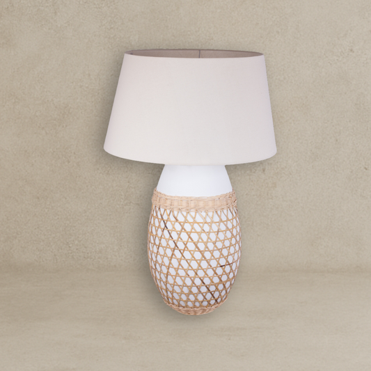 Lamp with woven base and white shade on a beige background