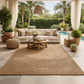 Outdoor patio with beige sectional sofa, round wooden coffee table, and decorative elements.