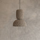 Textured pendant light hanging against a neutral wall