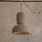 Textured pendant light hanging against a concrete wall