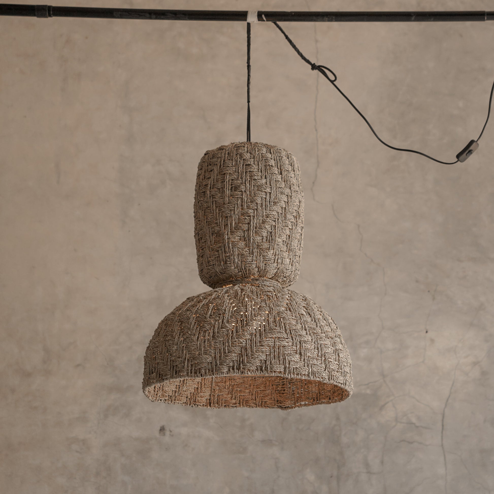 Textured pendant light hanging against a concrete wall