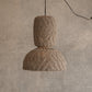 Woven pendant light hanging against a textured wall.