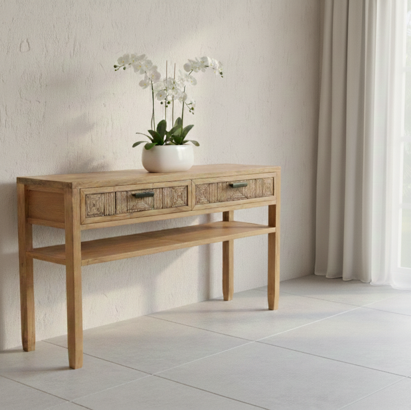 Wooden console table with a white pot of flowers against a light wall.