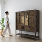 Woman walking past a wooden cabinet in a modern living room