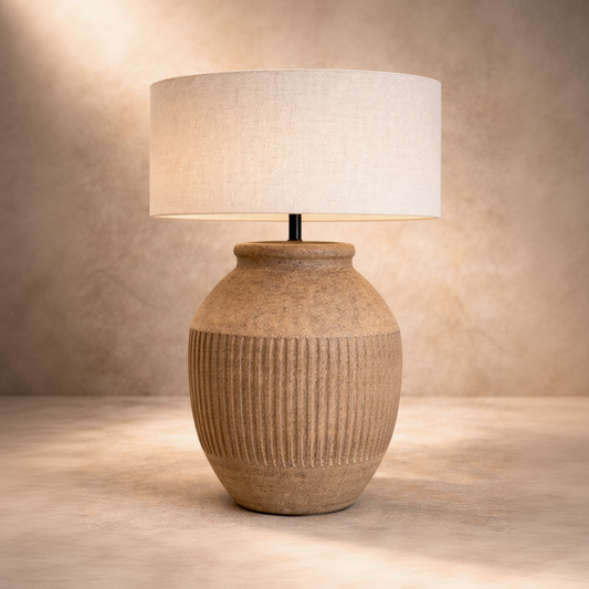 Table lamp with textured ceramic base and white shade on a neutral background