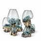 Set of glass vases with blue water on a wooden base against a white background