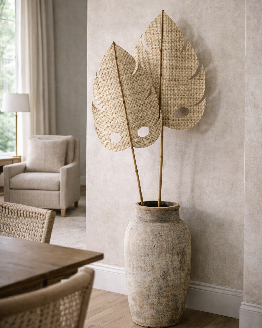 Decorative vase with leaf-shaped wicker pieces on a wall in a room with furniture and a window.