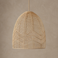 A woven pendant light with a natural rattan or wicker shade, suspended by a matching cord against a textured beige wall.