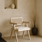 Wooden chair with woven backrest in a minimalistic room with a vase and plant.