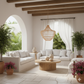 Modern living room with white sofas, wooden coffee table, and decorative plants.