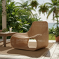 Woven chair on a wooden deck with plants and a table in the background