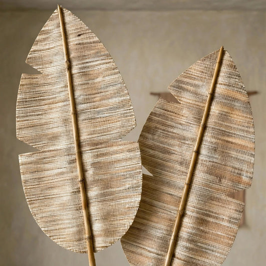 Two large decorative palm-leaf wall art pieces made from woven natural fiber and bamboo stakes, displayed against a neutral textured wall.