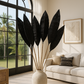 A decorative palm leaf accent with bamboo stem in a natural color, placed in a vase on a floor inside a room with tropical decor.