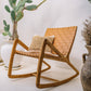 A solid teak wood frame relaxing chair with a leather seat, accompanied by a decorative cushion, positioned in a room with a cactus plant and decorative vases.