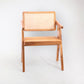 A rattan chair with handwoven rattan backrest and seat, teak wood frame, and armrests.