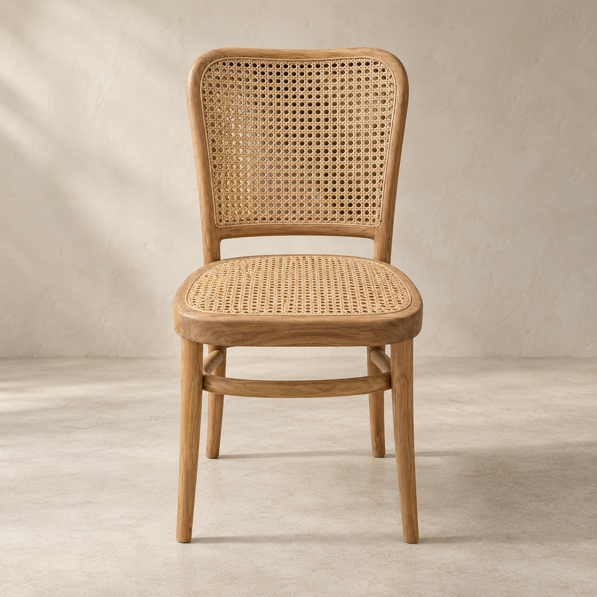 A classic wooden dining chair with a woven cane backrest and seat, shown from the front against a neutral textured beige wall and floor.
