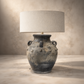 Table lamp with textured base and beige lampshade on a neutral background