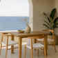Dining area with wooden table and chairs by a large archway overlooking the ocean.