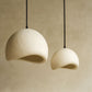 Two white pendant lights hanging against a beige wall.